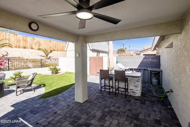 view of patio featuring an outdoor kitchen, ceiling fan, and a bar