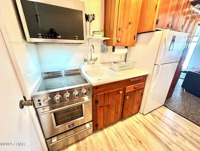 9378 Riverside Dr, Parker, AZ 85344 - kitchen with appliances with stainless steel finishes, brown cabinetry, light countertops, and light wood-style floors