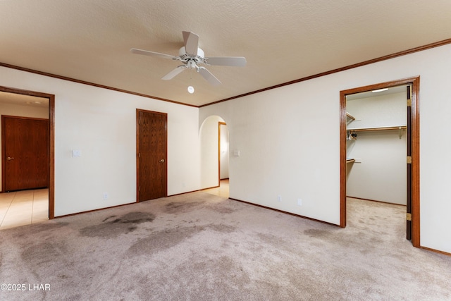 unfurnished bedroom with baseboards, carpet floors, arched walkways, a closet, and a textured ceiling