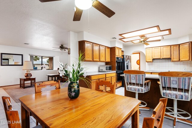 dining room with visible vents, arched walkways, light tile patterned flooring, and a ceiling fan