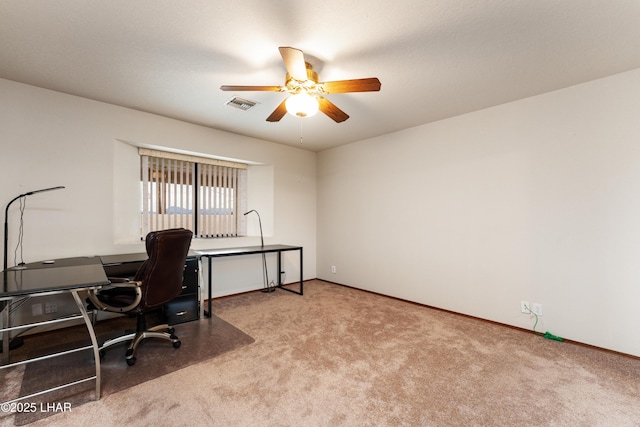 carpeted office space featuring baseboards, visible vents, and ceiling fan