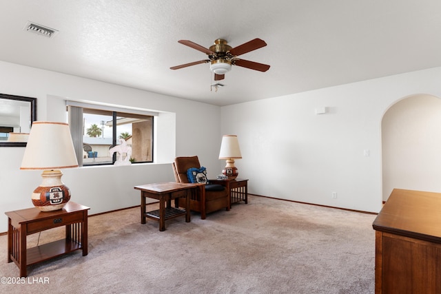 office space featuring visible vents, baseboards, ceiling fan, carpet flooring, and arched walkways