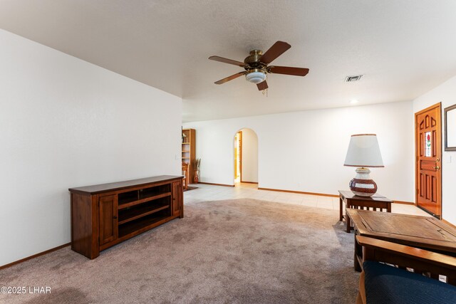 living area featuring light carpet, visible vents, arched walkways, and a ceiling fan