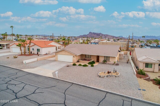 view of front of house with fence, a residential view, concrete driveway, stucco siding, and a mountain view