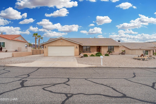 view of front facade with fence, a garage, driveway, and stucco siding