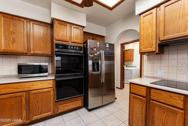 kitchen featuring brown cabinets, separate washer and dryer, black appliances, and light countertops