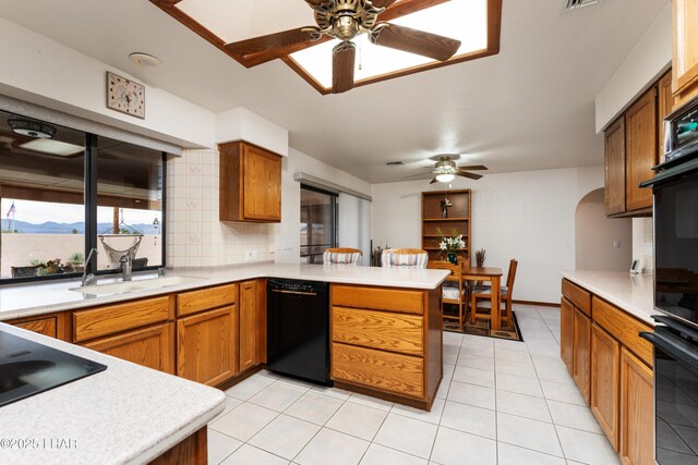 kitchen with a sink, brown cabinets, black appliances, and a peninsula