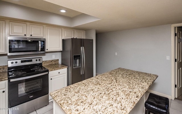 kitchen featuring light stone counters, stainless steel appliances, and a kitchen breakfast bar