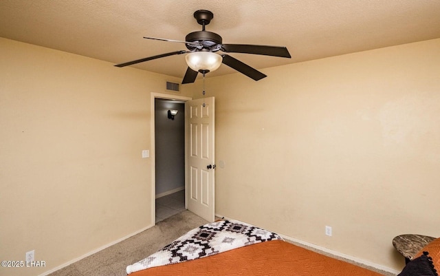 unfurnished bedroom featuring ceiling fan, light colored carpet, and a textured ceiling