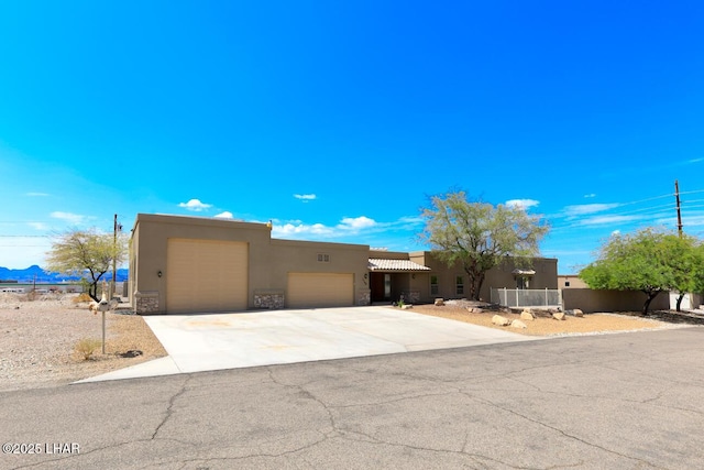 adobe home with driveway, stone siding, an attached garage, and stucco siding