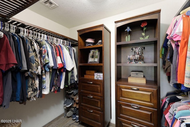 walk in closet with visible vents and wood finished floors