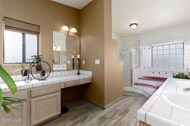 full bath featuring a sink, double vanity, wood finished floors, and a shower stall