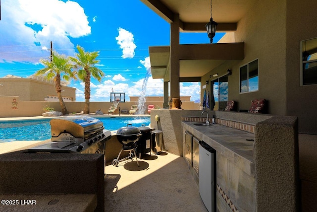 view of swimming pool with a fenced in pool, a patio, a sink, fence, and exterior kitchen