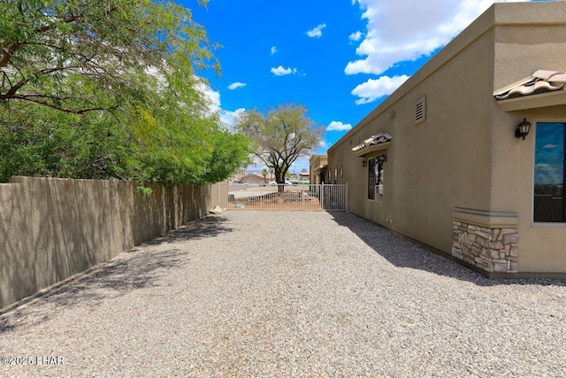 view of property exterior with a gate, fence, and stucco siding