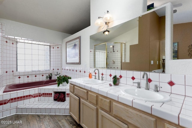 bathroom with a stall shower, a garden tub, a sink, and wood finished floors