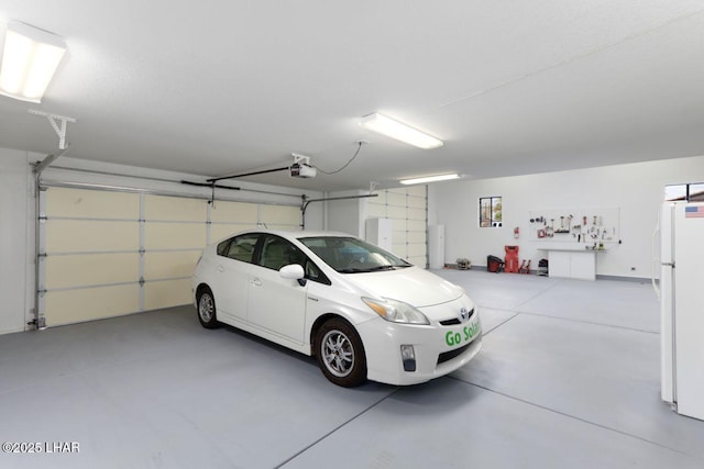 garage with a garage door opener and freestanding refrigerator