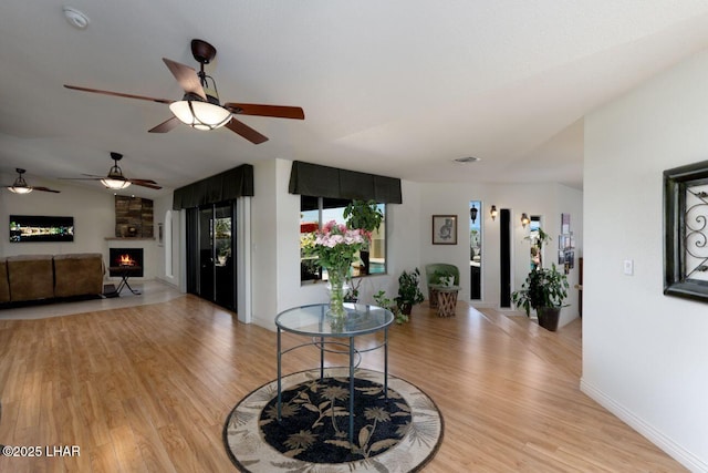 living room with light wood-type flooring, a warm lit fireplace, and baseboards