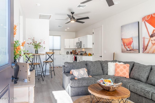 living room featuring ceiling fan and light hardwood / wood-style flooring