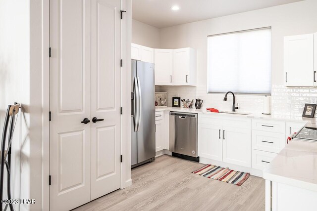 kitchen featuring sink, light hardwood / wood-style flooring, stainless steel appliances, and white cabinets