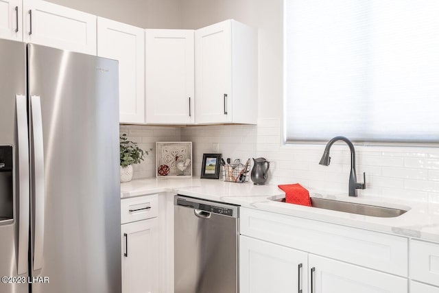 kitchen with sink, tasteful backsplash, stainless steel appliances, light stone countertops, and white cabinets