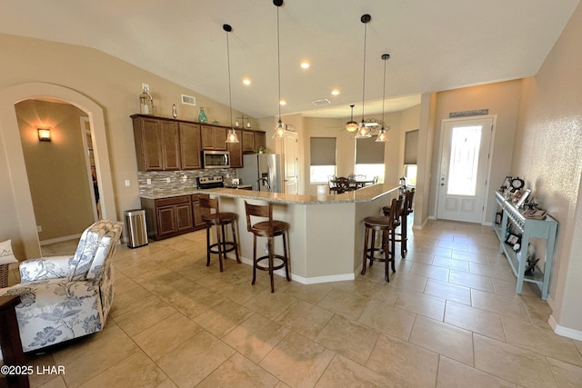 2969 Pony Cir, Lake Havasu City, AZ 86406 - kitchen with stainless steel appliances, arched walkways, decorative backsplash, a breakfast bar area, and vaulted ceiling