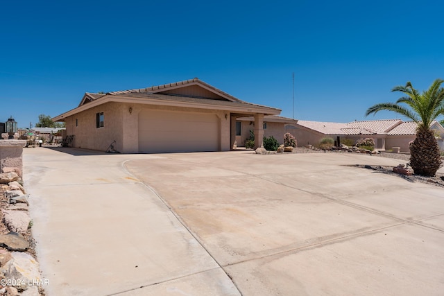 view of front of property featuring a garage, a tile roof, concrete driveway, and stucco siding