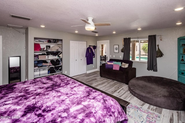 bedroom with ceiling fan, light hardwood / wood-style floors, and a textured ceiling