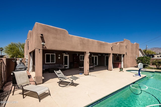 rear view of property with an outdoor hangout area, a patio area, and a pool with hot tub