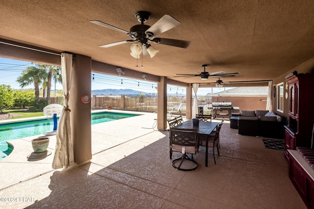 view of patio / terrace featuring ceiling fan, outdoor lounge area, a fenced in pool, and a mountain view