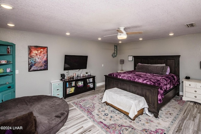 bedroom featuring ceiling fan, a textured ceiling, and light hardwood / wood-style floors