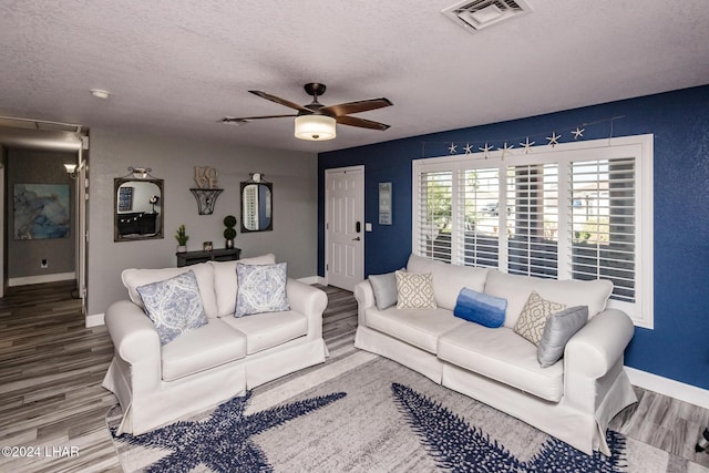 living room with ceiling fan, wood-type flooring, and a textured ceiling