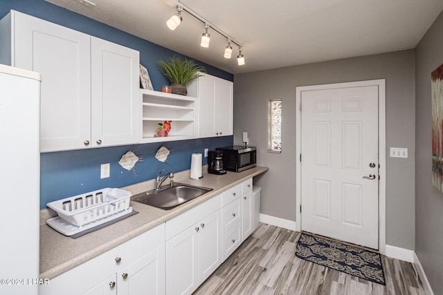 kitchen featuring rail lighting, sink, white cabinets, fridge, and light wood-type flooring