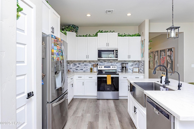 kitchen with tasteful backsplash, visible vents, stainless steel appliances, light countertops, and white cabinetry