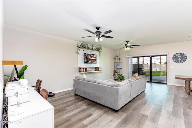 living area featuring baseboards, visible vents, and light wood-style floors