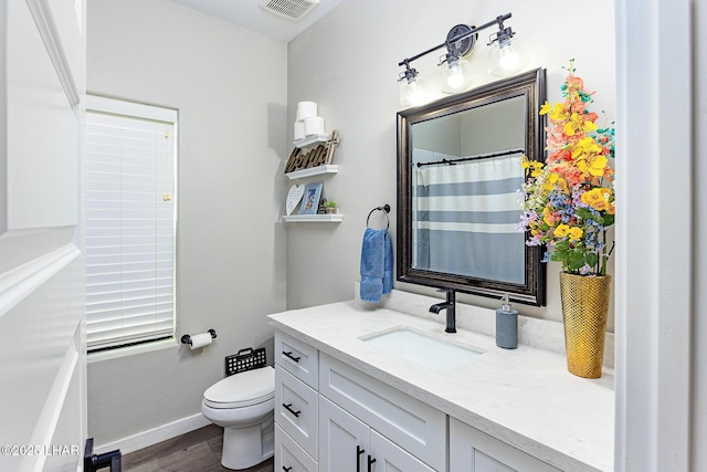 full bathroom with visible vents, toilet, vanity, wood finished floors, and baseboards