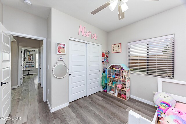 bedroom featuring a ceiling fan, a closet, light wood-style flooring, and baseboards