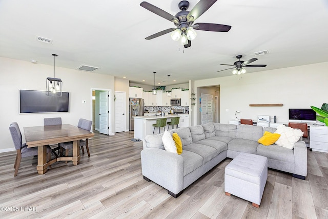 living area with a ceiling fan, visible vents, and light wood-style flooring