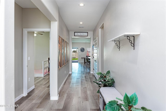 hall with light wood-style flooring, visible vents, baseboards, and recessed lighting