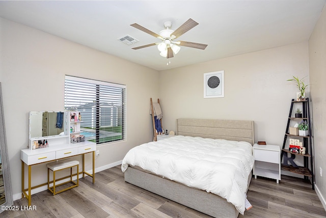 bedroom featuring a ceiling fan, wood finished floors, visible vents, and baseboards