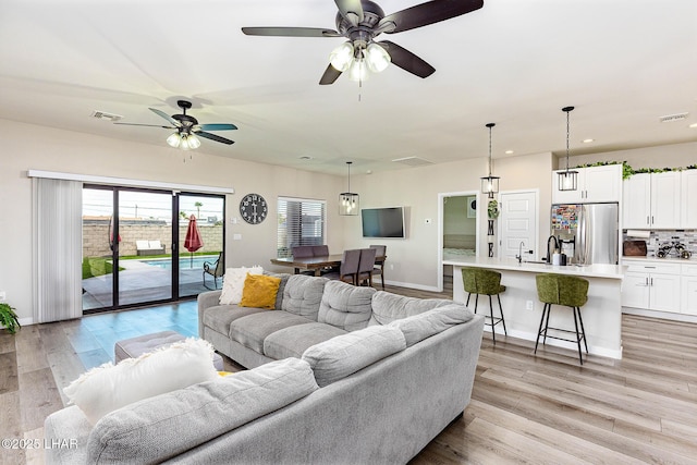 living room with light wood-style flooring, visible vents, and recessed lighting