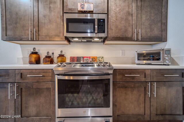 kitchen with dark brown cabinetry, stainless steel appliances, and extractor fan