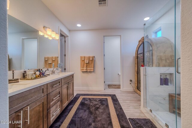 bathroom featuring wood-type flooring, an enclosed shower, and vanity