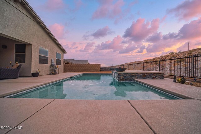 pool at dusk featuring a patio