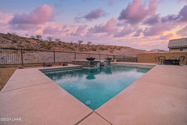 pool at dusk featuring a patio area