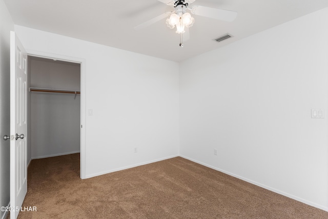 unfurnished bedroom featuring a spacious closet, carpet floors, a closet, and ceiling fan