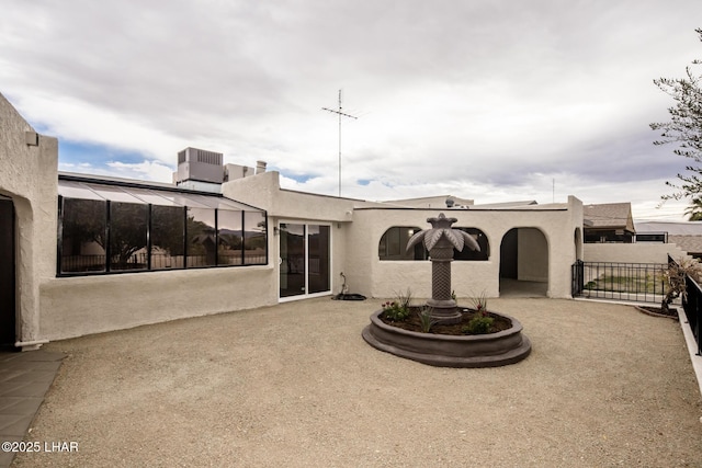 back of house with stucco siding, central air condition unit, a gate, fence, and a patio area