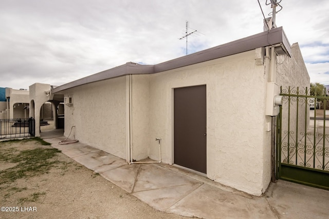 back of property featuring a gate, fence, and stucco siding