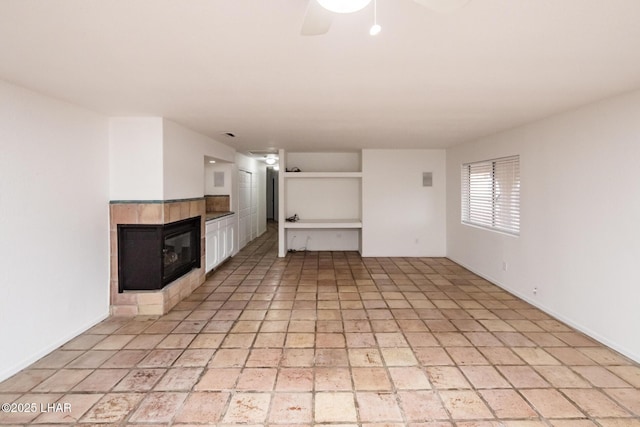 unfurnished living room featuring a tiled fireplace and a ceiling fan