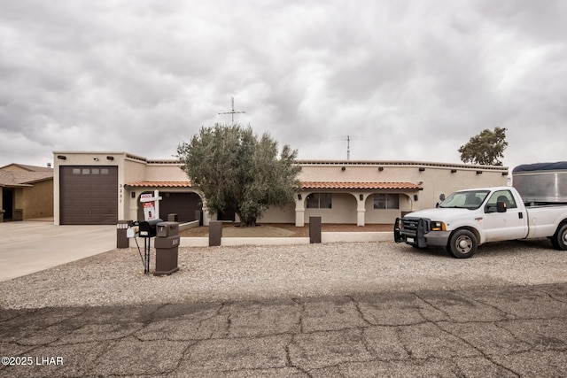 view of front facade featuring a tiled roof, a garage, driveway, and stucco siding