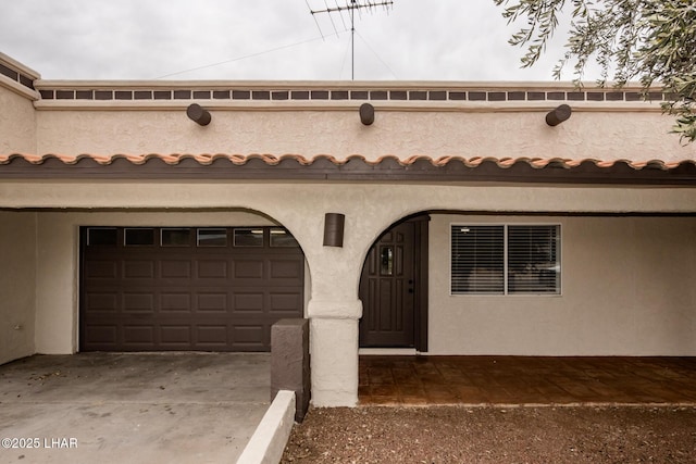 view of front of home with a tile roof, stucco siding, concrete driveway, and a garage